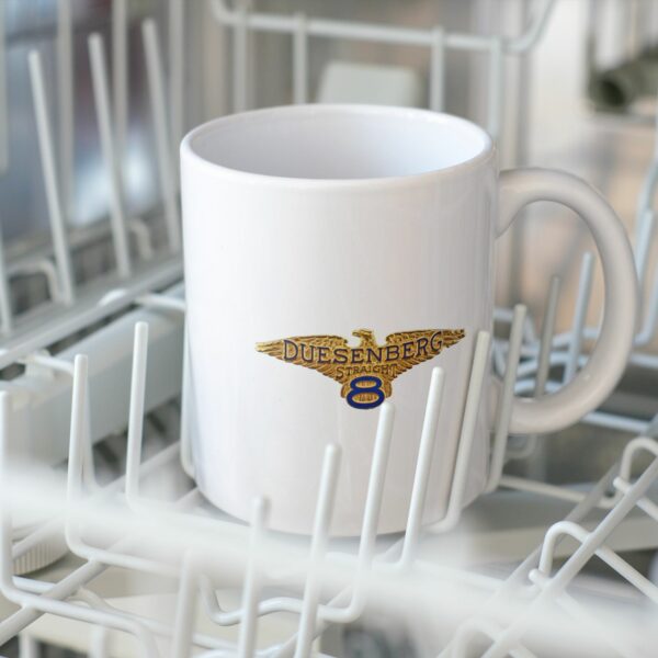White 11oz ceramic coffee mug with Duesenberg vintage car logo in gold and blue, kitchen background.