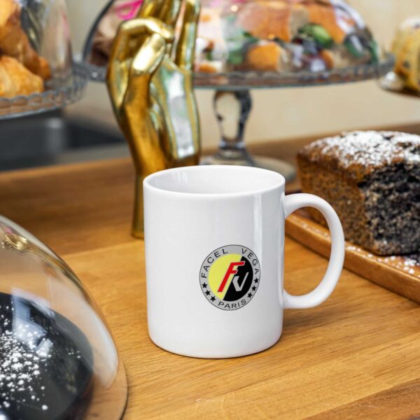 Sleek white 11oz ceramic mug featuring the colorful Facel Vega emblem, on a kitchen counter backdrop.