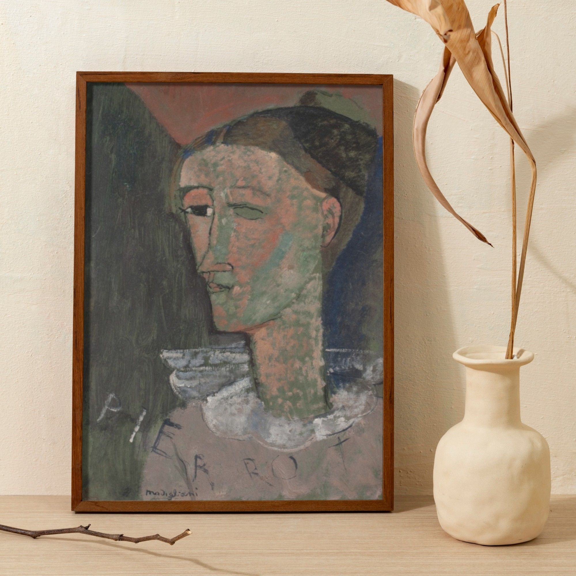 Amedeo Modigliani's self-portrait as Pierrot, showing the artist's interpretation of the traditional comical character with abstracted and muted features set against a dark background. The painter's use of contrasting green and red patches on the face, and the inscribed word 'PIERROT' at the bottom, convey a modernist twist on the classic theme.