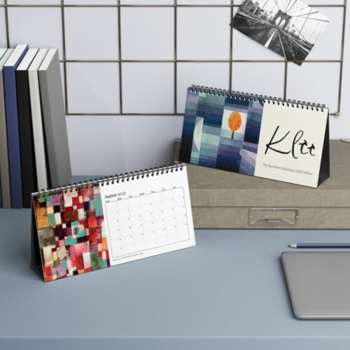 2025 edition Paul Klee collection desk calendar displayed upright, featuring abstract geometric artwork with cool blue and purple tones and a contrasting warm orange circle.
