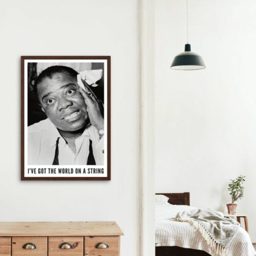 Black and white photo of Louis Armstrong with a playful expression, hand on his cheek, text reads I'VE GOT THE WORLD ON A STRING, white shirt and suspenders, conveying charm and charisma.