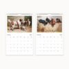 Open wall calendar showing January and February months of 2025 with paintings of playful dogs and puppies by Carl Reichert, each month laid out with a simple grid for dates.