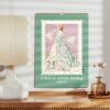 Calendar for A Year in Artistic Postage Edition 2025 featuring a vintage dress stamp design on a desk beside a lamp and vase