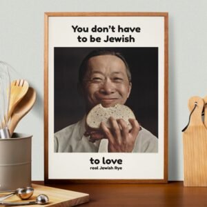 Smiling man holding rye bread sandwich.