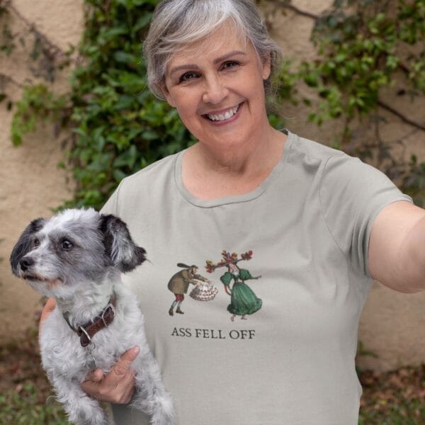 Smiling woman holding dog wearing funny shirt.