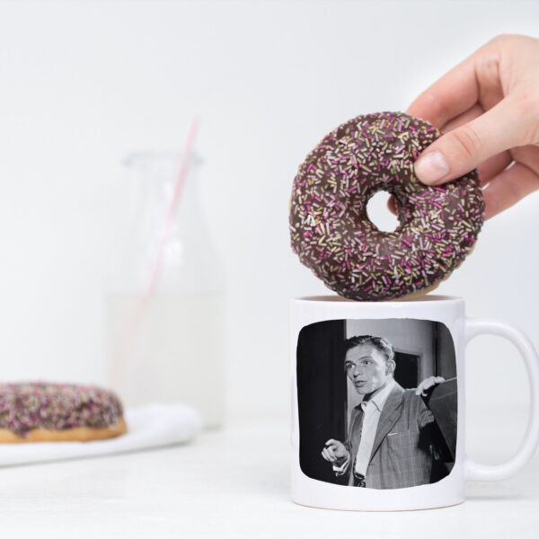 Hand holding donut over mug with photo