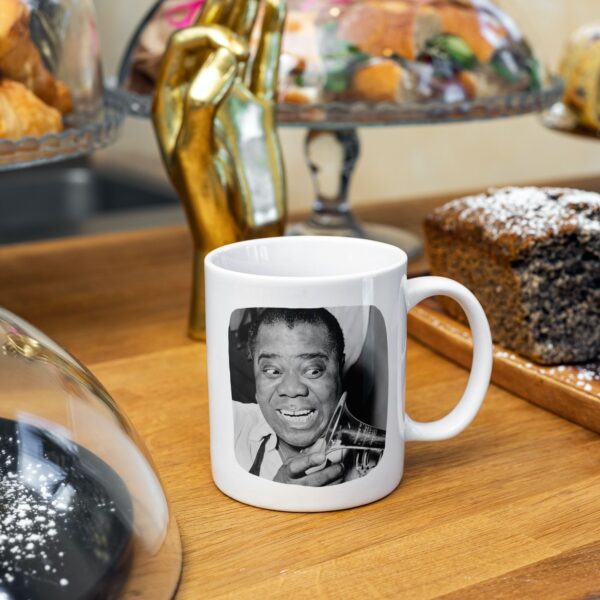 Mug with Louis Armstrong's face amidst desserts and decor.