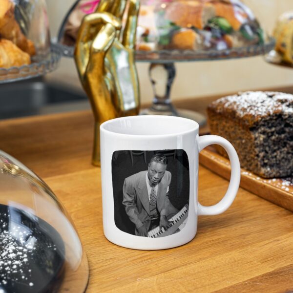 Mug with Nat King Cole photo on wooden table with pastries.