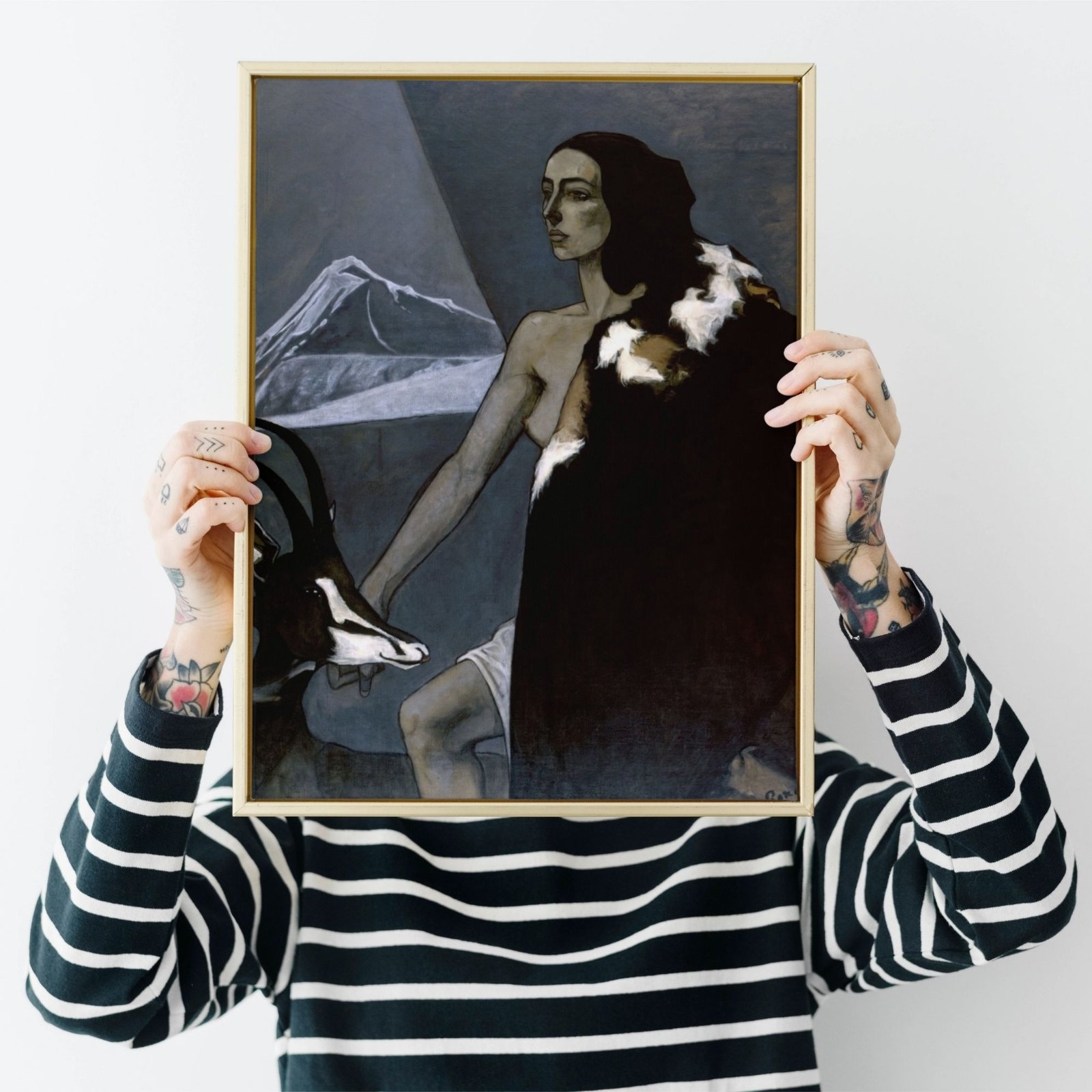 Person holding a framed painting with tattoos visible.