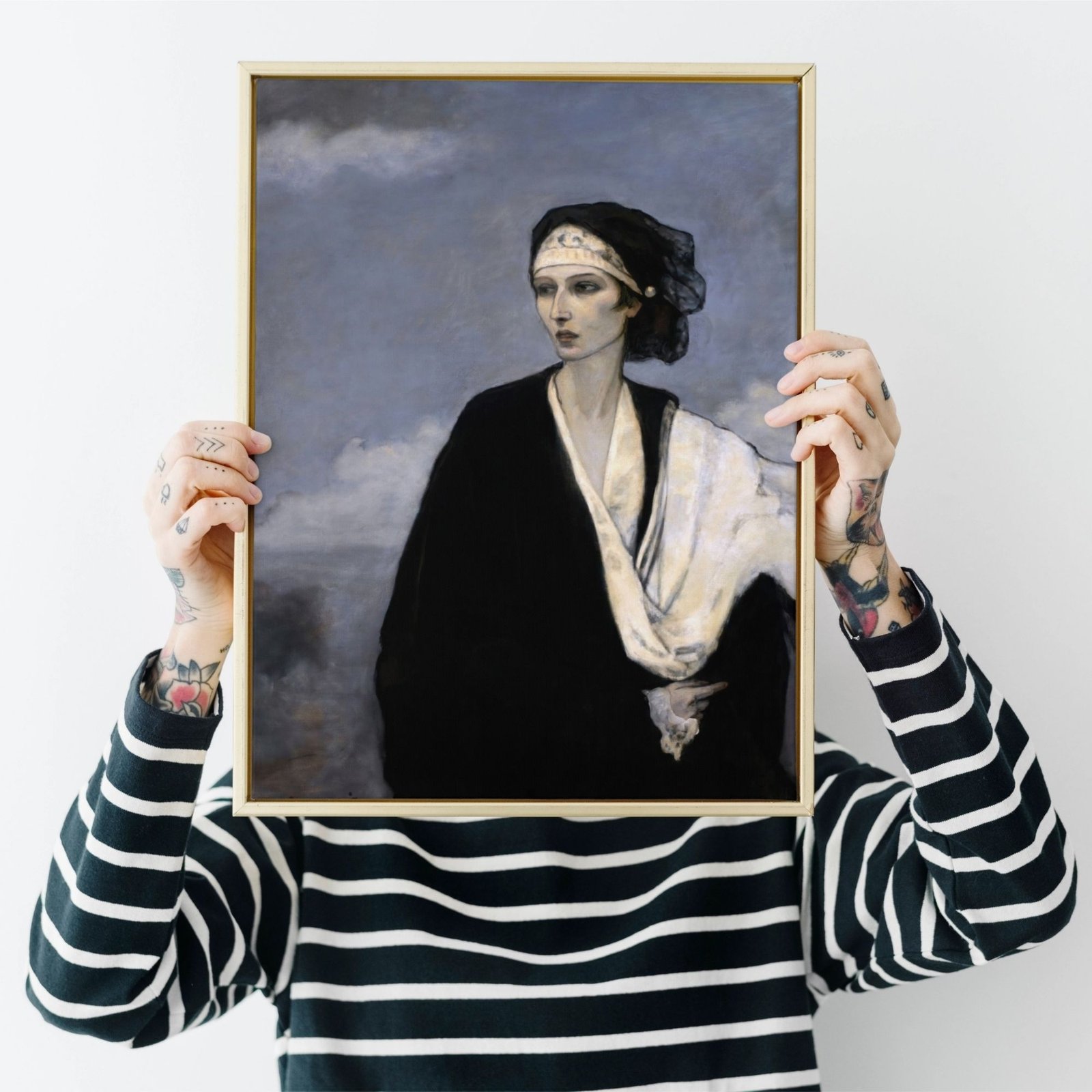 Tattooed person holding a framed portrait over face.