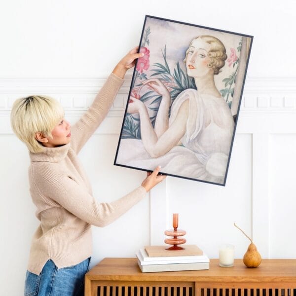 Elegant 1920s lady in white dress holding a sprig of pink flowers by Gerda Wegener, showcasing Art Deco style and femininity.