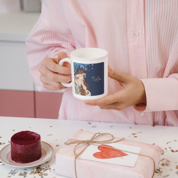 Woman holding artistic mug near gift and dessert.