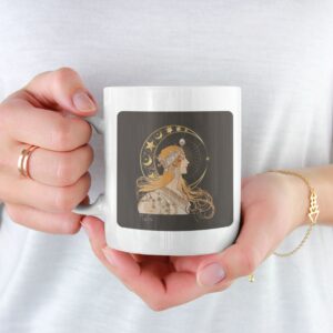 Mug with Mucha-style celestial illustration held by hand.