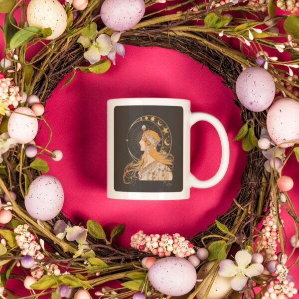 Decorative mug inside floral Easter wreath on pink background.