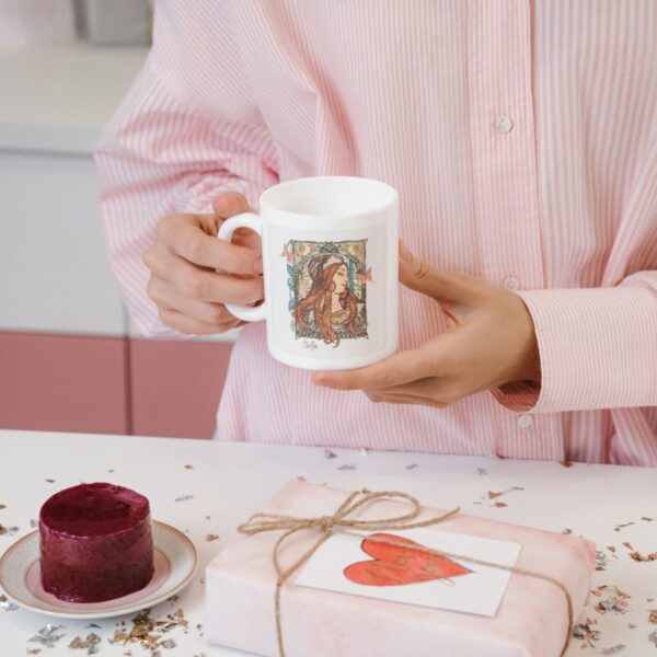 Person holding mug near dessert and gift box.