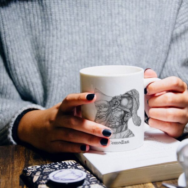 Person holding a mug over a book