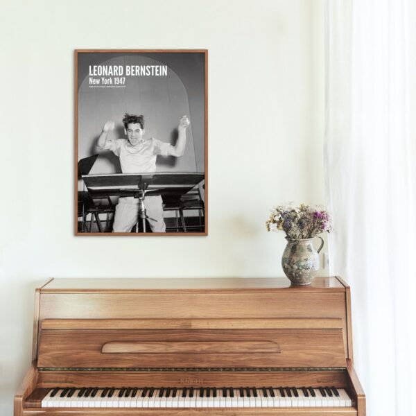 Framed photo of Leonard Bernstein above wooden piano with flowers vase