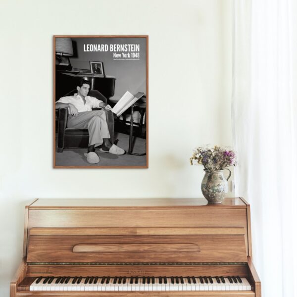 Framed 1948 photo of Leonard Bernstein above wooden piano and vase.