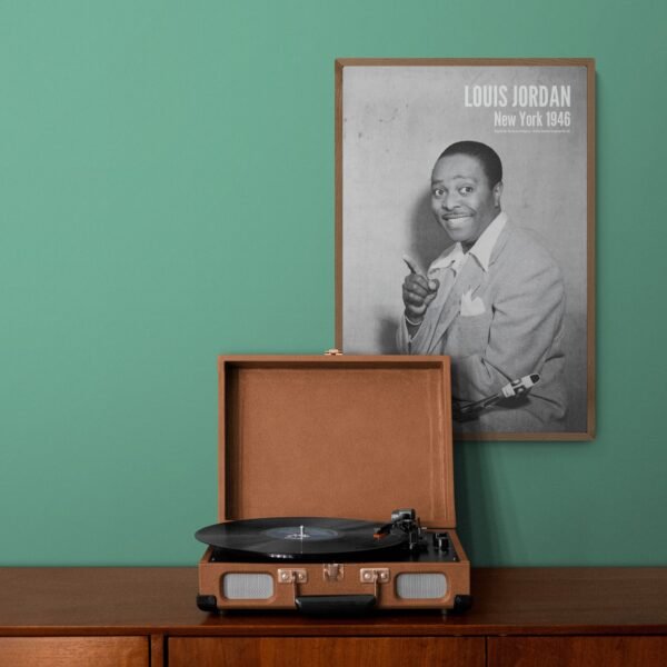 Turntable with vintage jazz poster of Louis Jordan on wall.