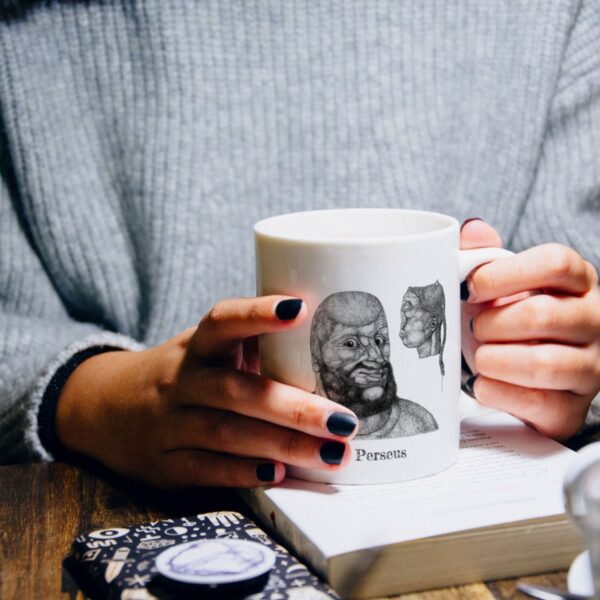 Person holding Perseus mug over a book