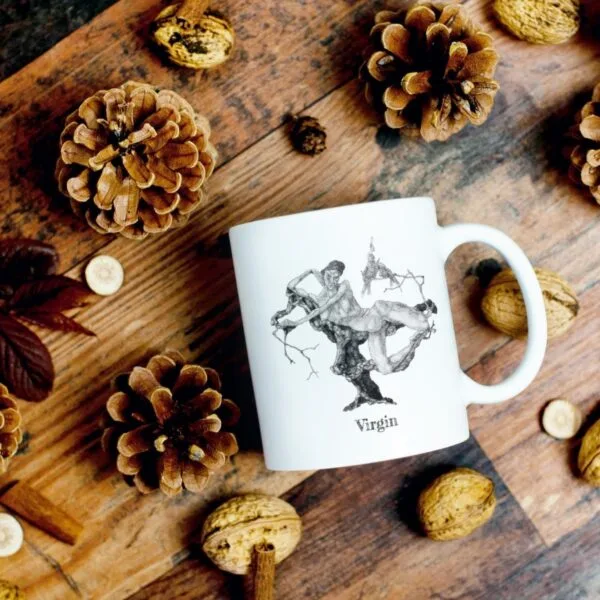 White mug with artwork surrounded by pine cones.