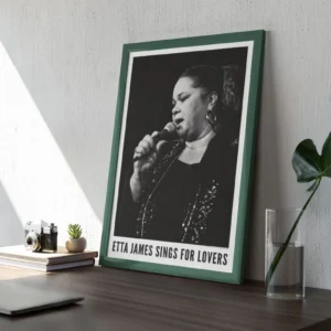 Framed Etta James poster on wooden desk.