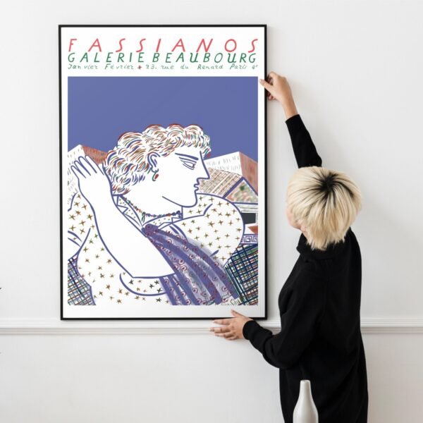 Person hanging framed artwork on wall.