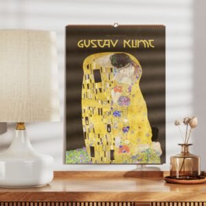 Gustav Klimt art calendar by lamp on wooden table.
