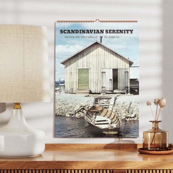 Calendar with Nordic cabin scenery on wall.
