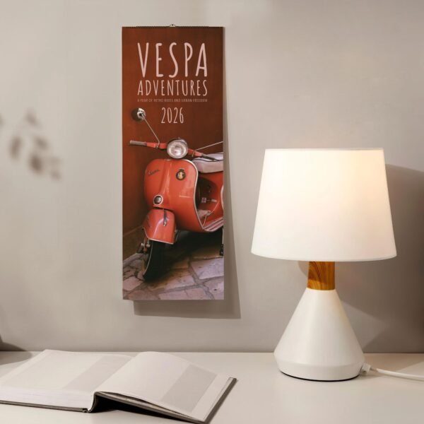 Vespa Adventures 2026 calendar, lamp, and open book.