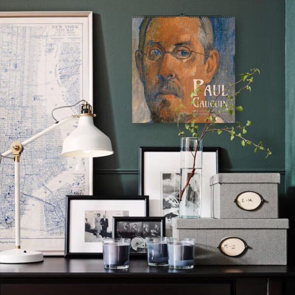 Desk with lamp, art, candles, and storage boxes.