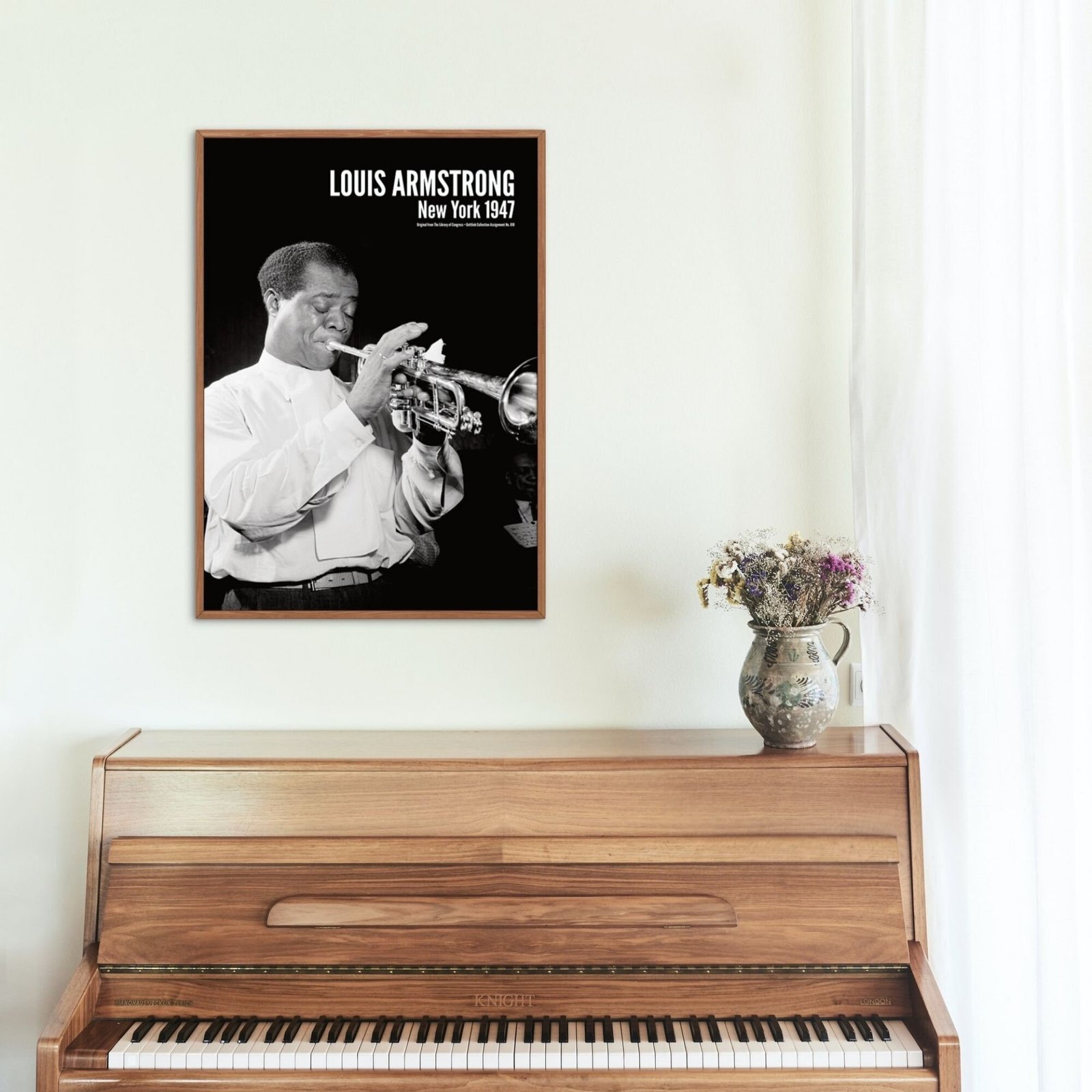 Framed trumpet player photo above wooden piano.