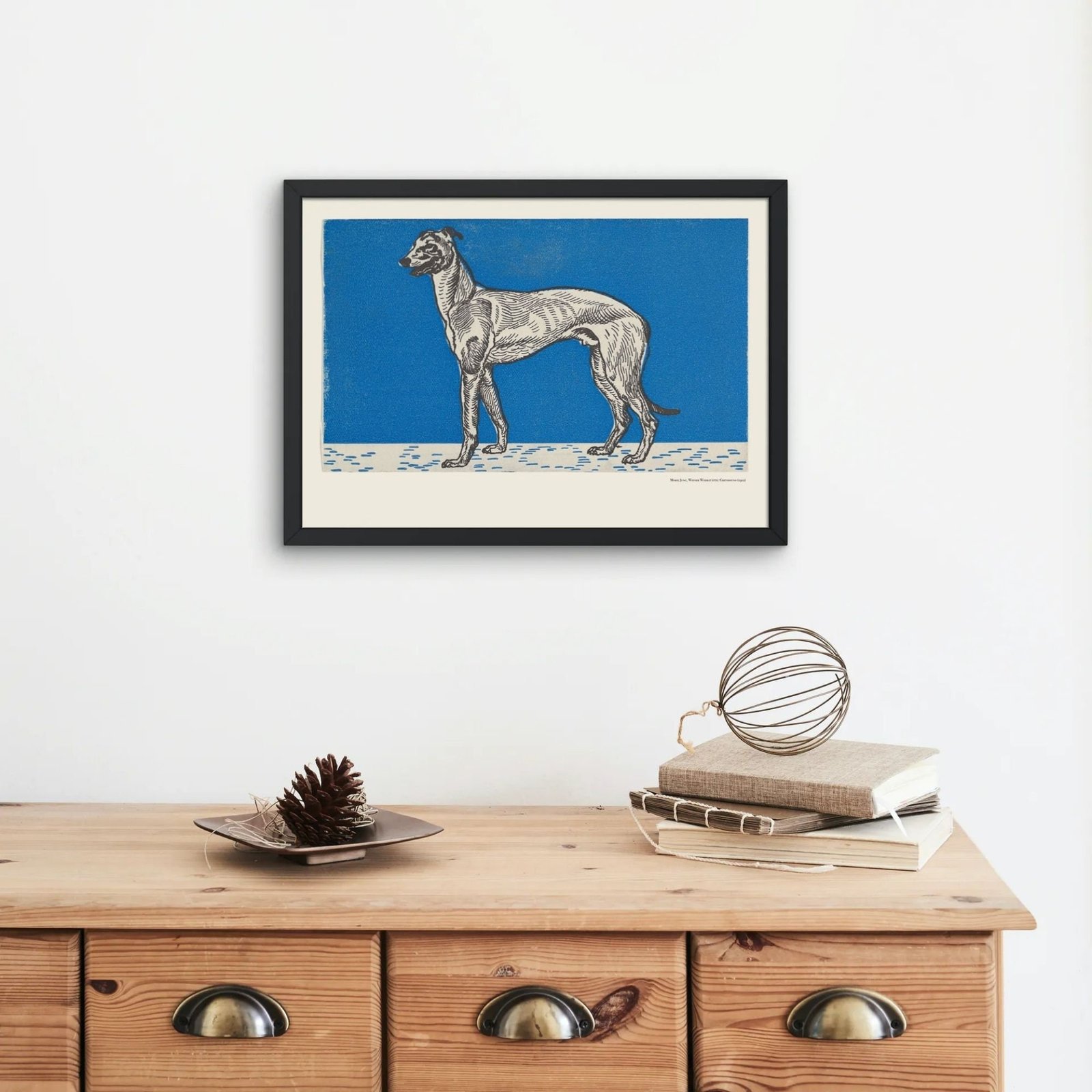 Framed dog artwork on wooden dresser with decor.