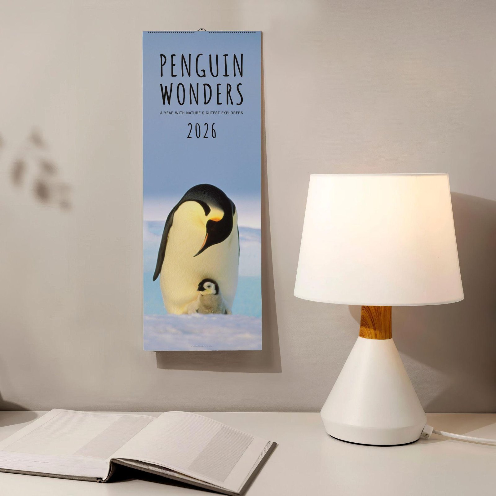 Penguin Wonders 2026 calendar near lamp and book.