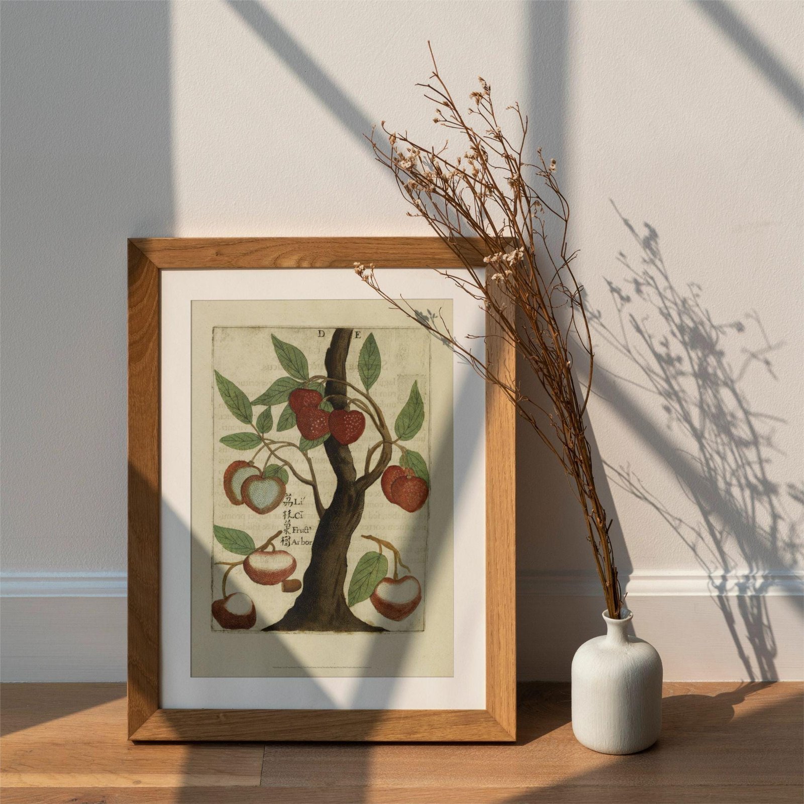 Framed botanical art with vase on wooden floor.
