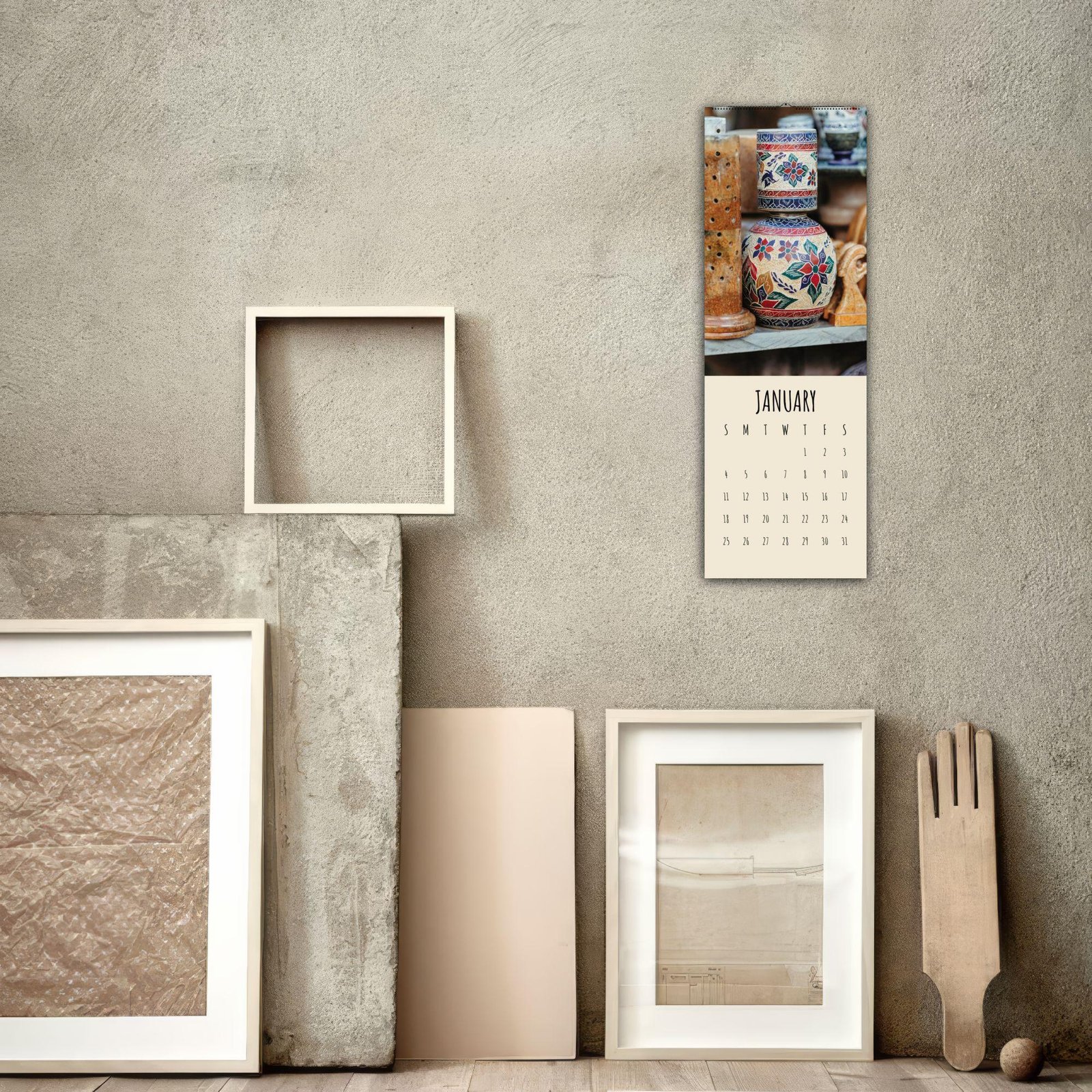 Wall calendar and art frames on textured wall.