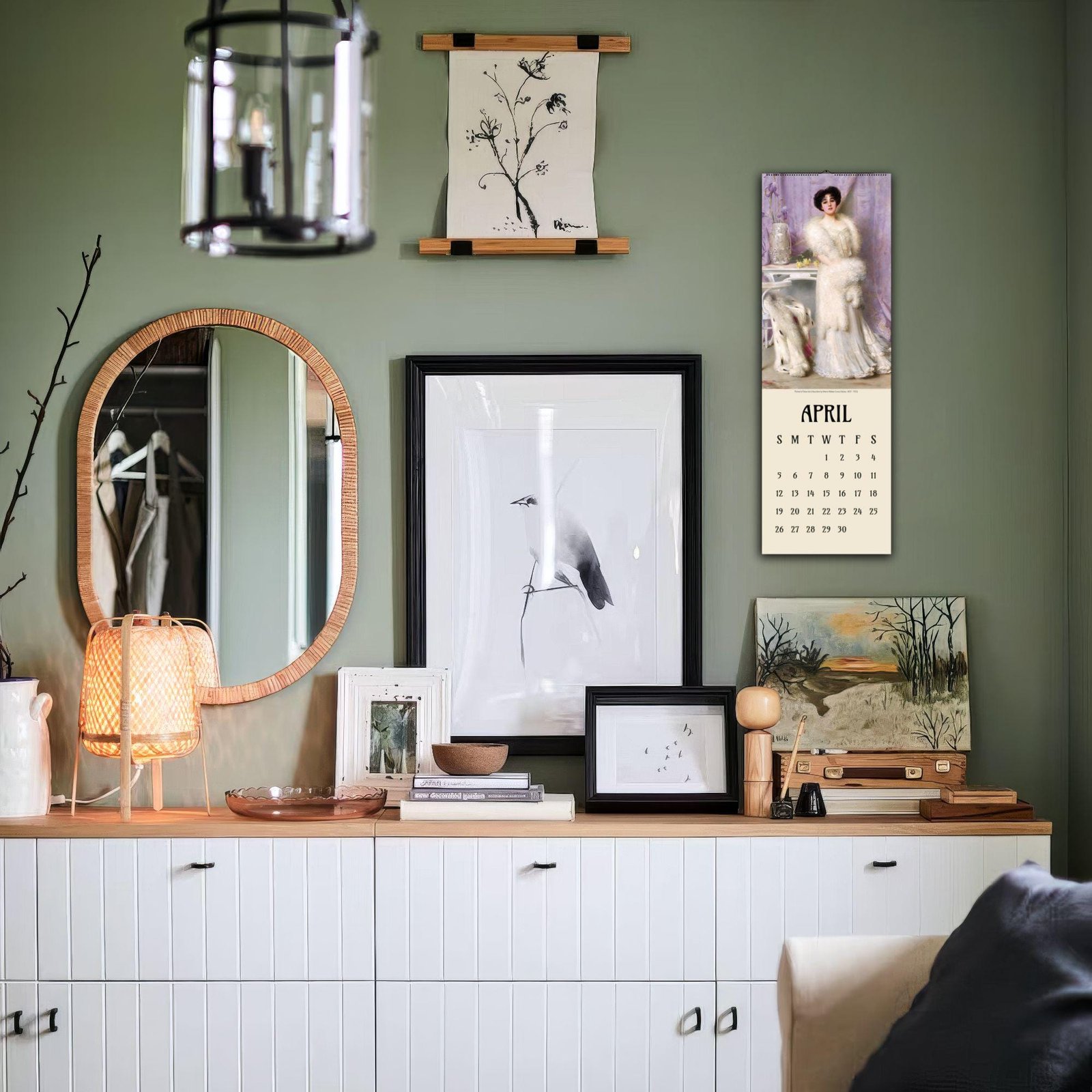 Decorative wall with art and calendar above cabinet.