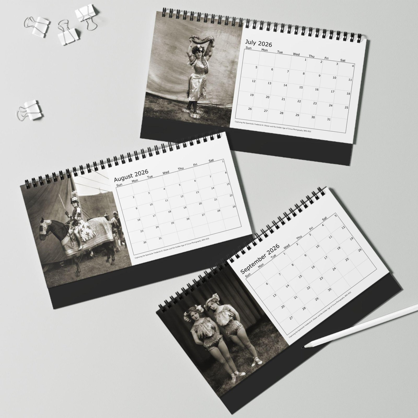 Three 2026 calendars on a desk with black-and-white photos.
