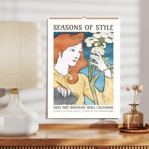 Art Nouveau wall calendar 2027 on wooden table.