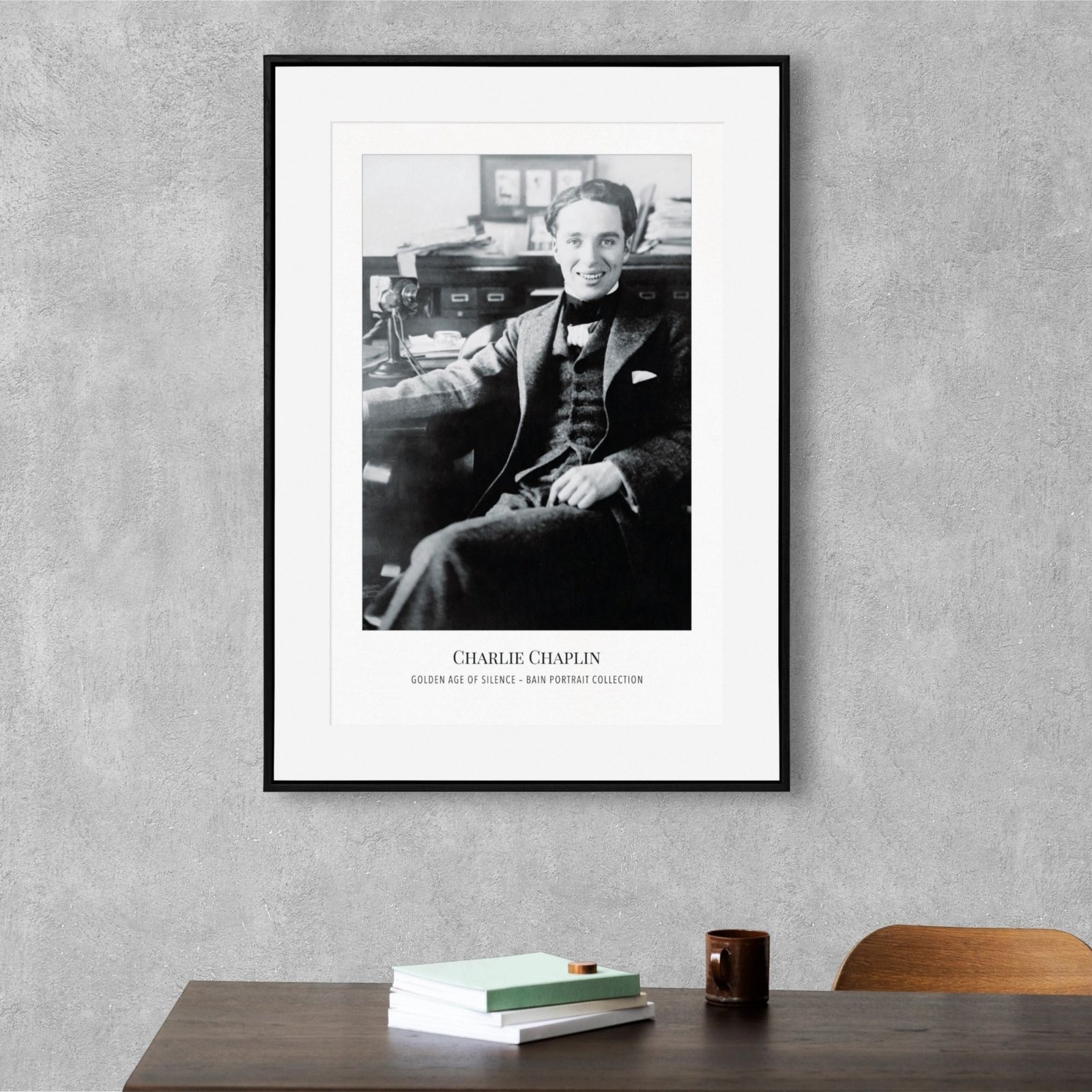 Framed Charlie Chaplin portrait on gray wall.