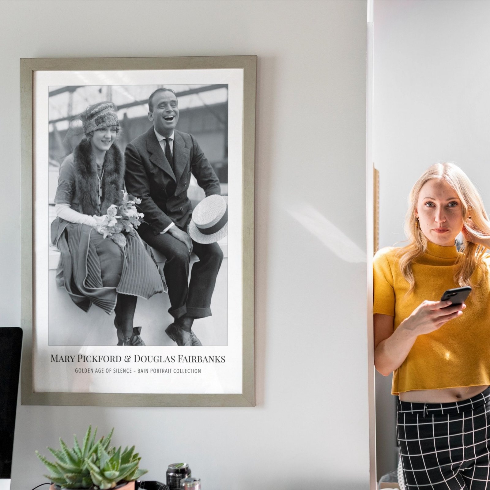 Woman standing near vintage poster, using smartphone.