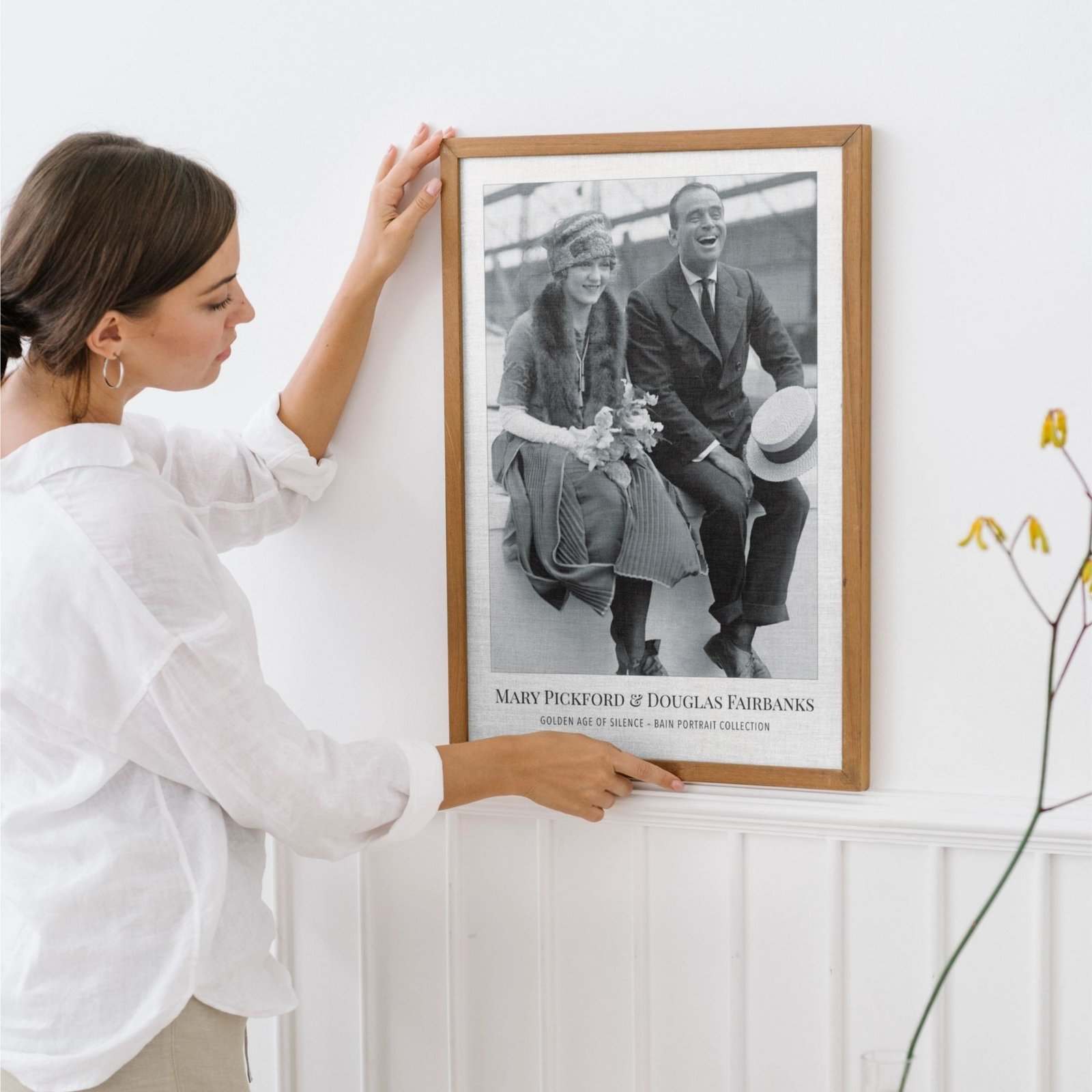 Woman hanging framed vintage photograph on wall.