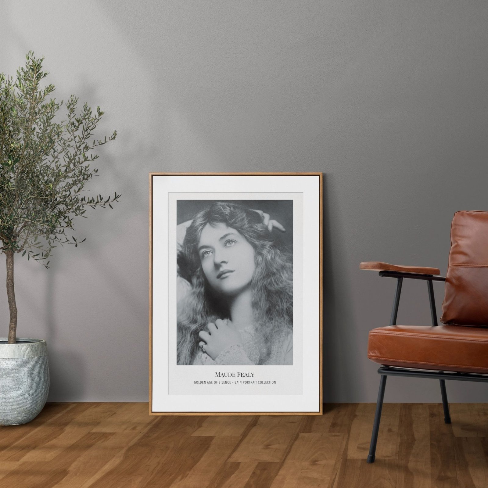 Framed portrait of woman beside chair and plant.