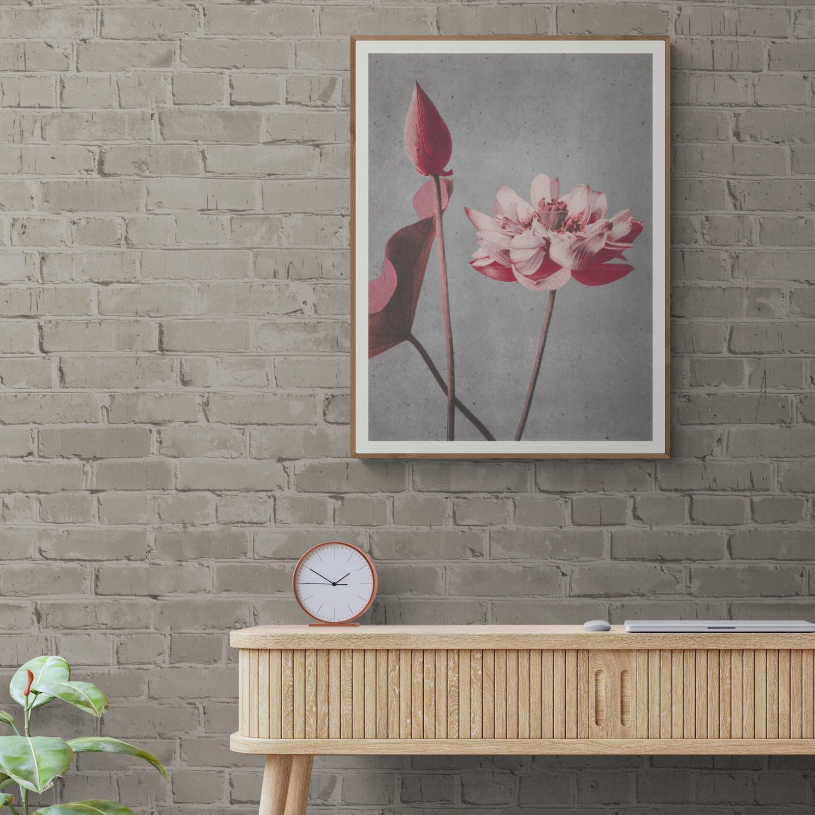 Framed flower art on brick wall above desk.