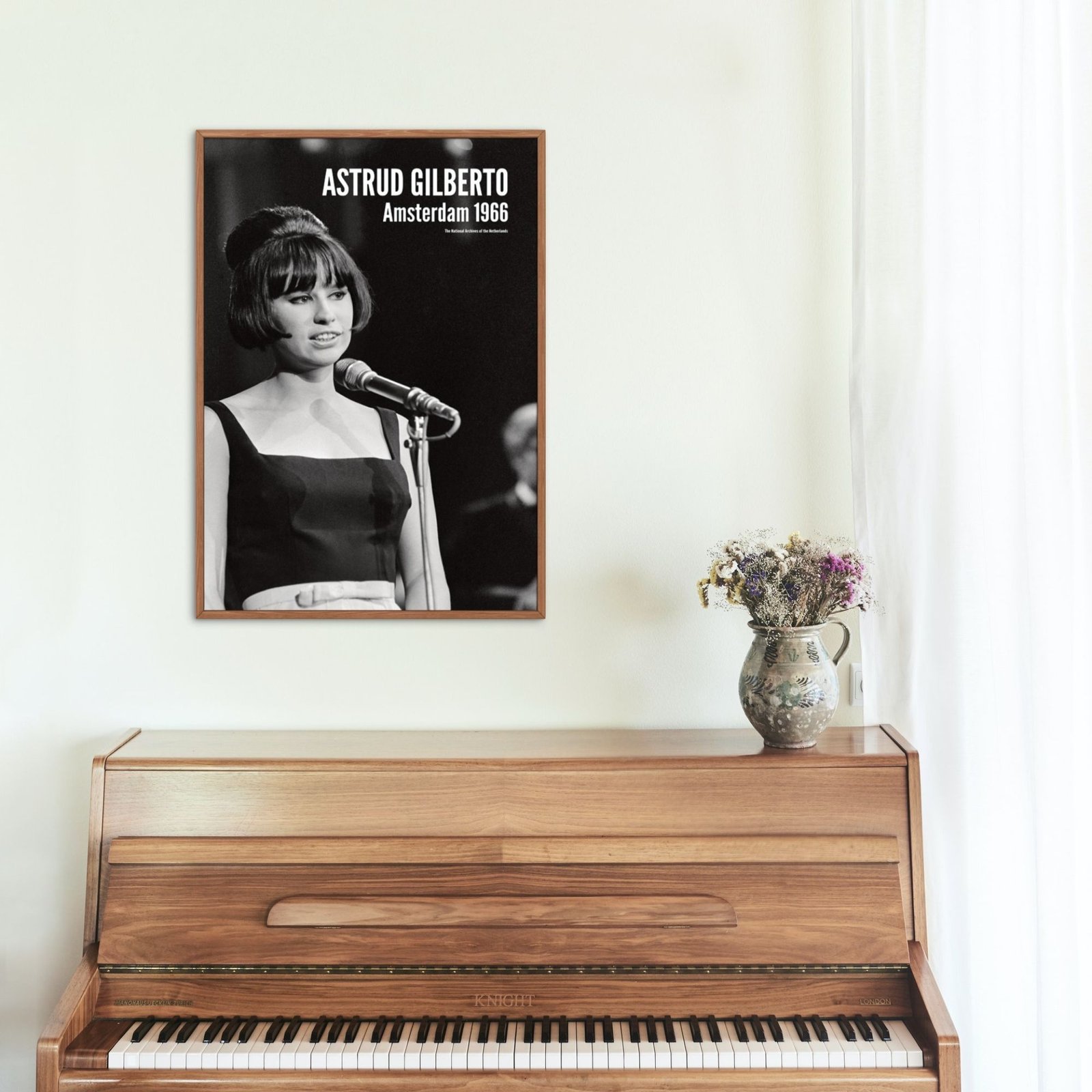 Framed photo above wooden piano with flowers.
