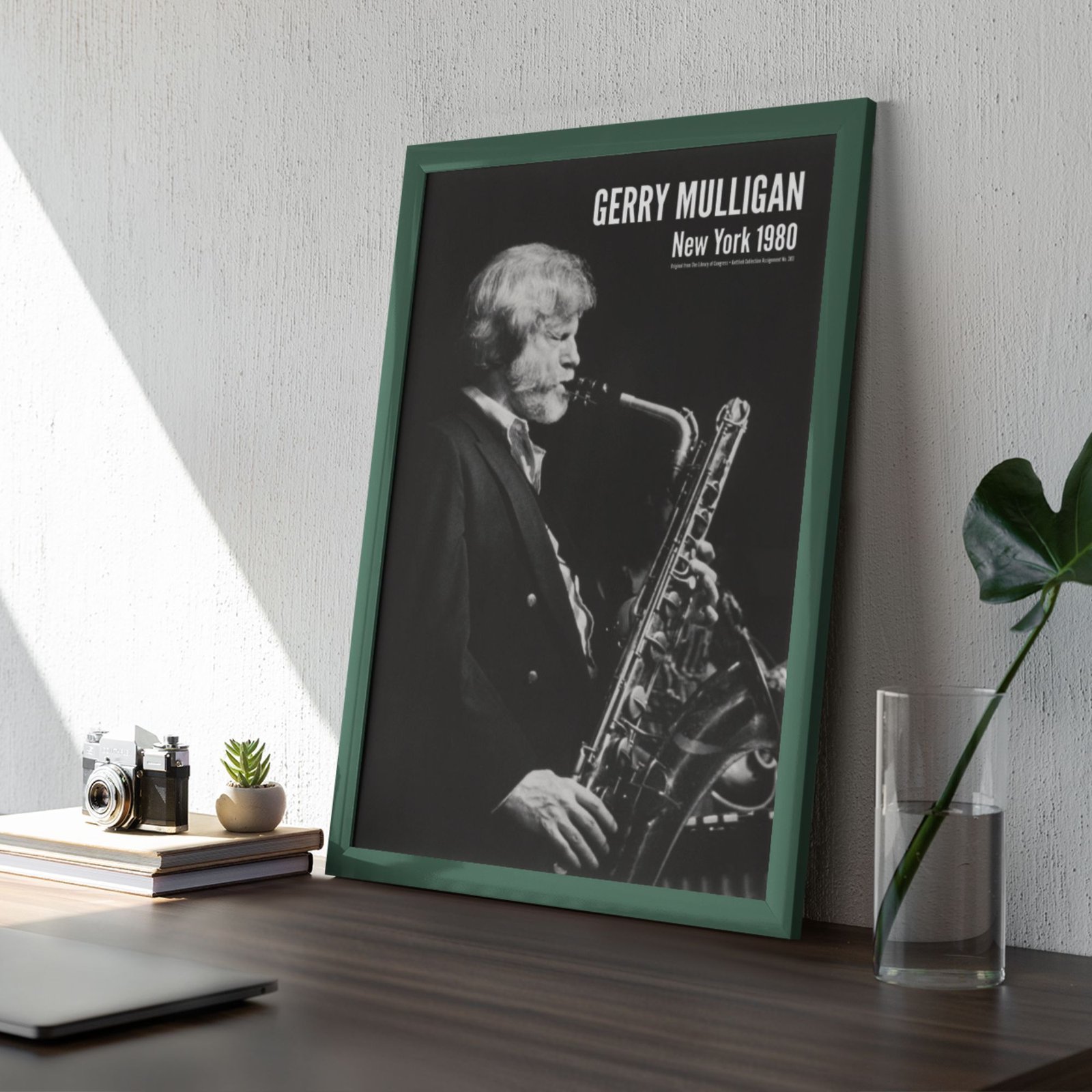 Framed black and white saxophonist poster on desk.