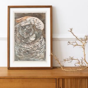 Framed parrot artwork on wooden sideboard