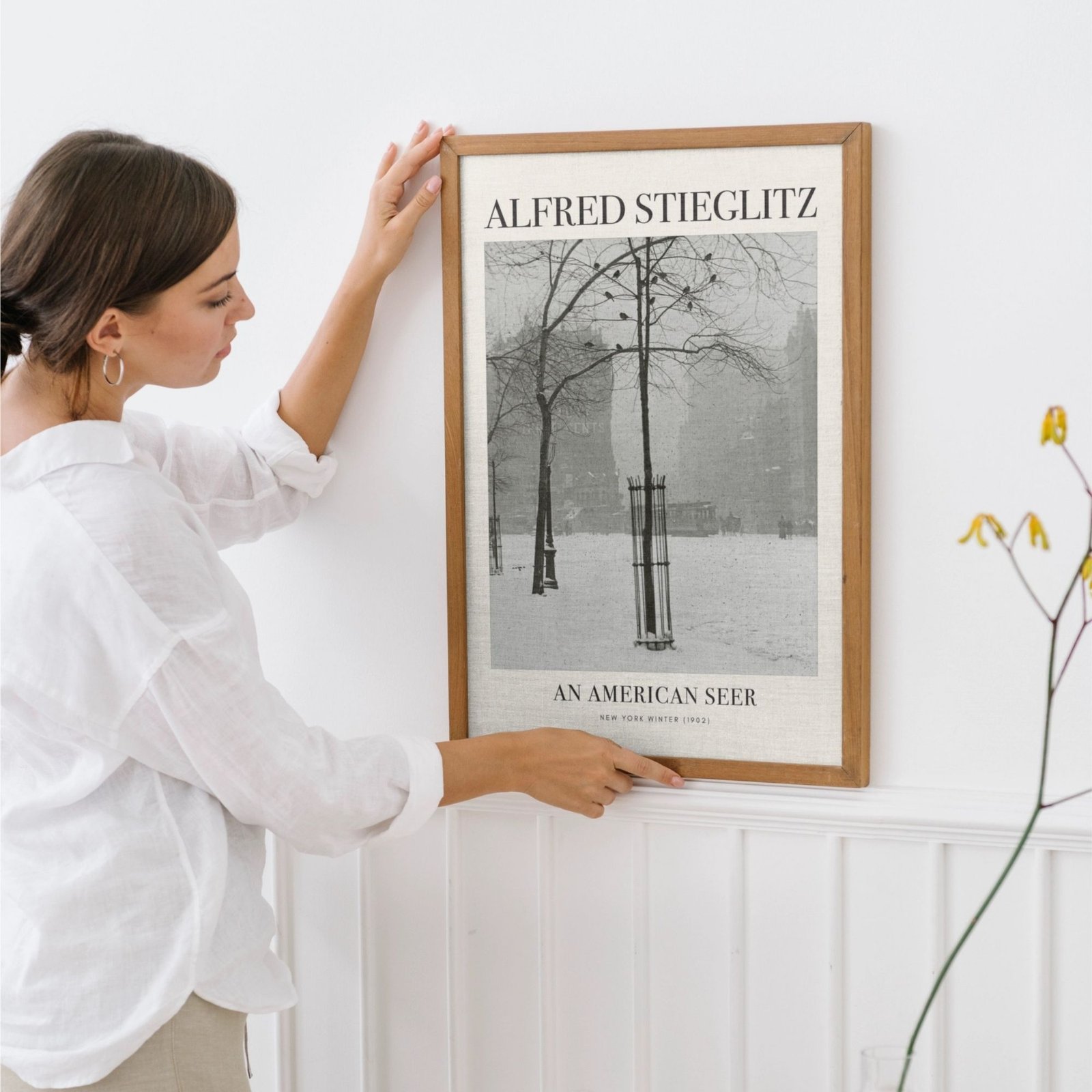 Woman hanging Alfred Stieglitz framed photo on wall
