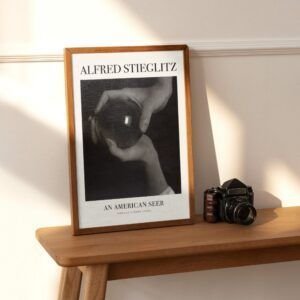 Framed Alfred Stieglitz photo beside vintage camera.