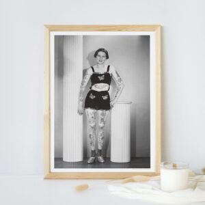 Framed vintage photo of tattooed woman in shorts.